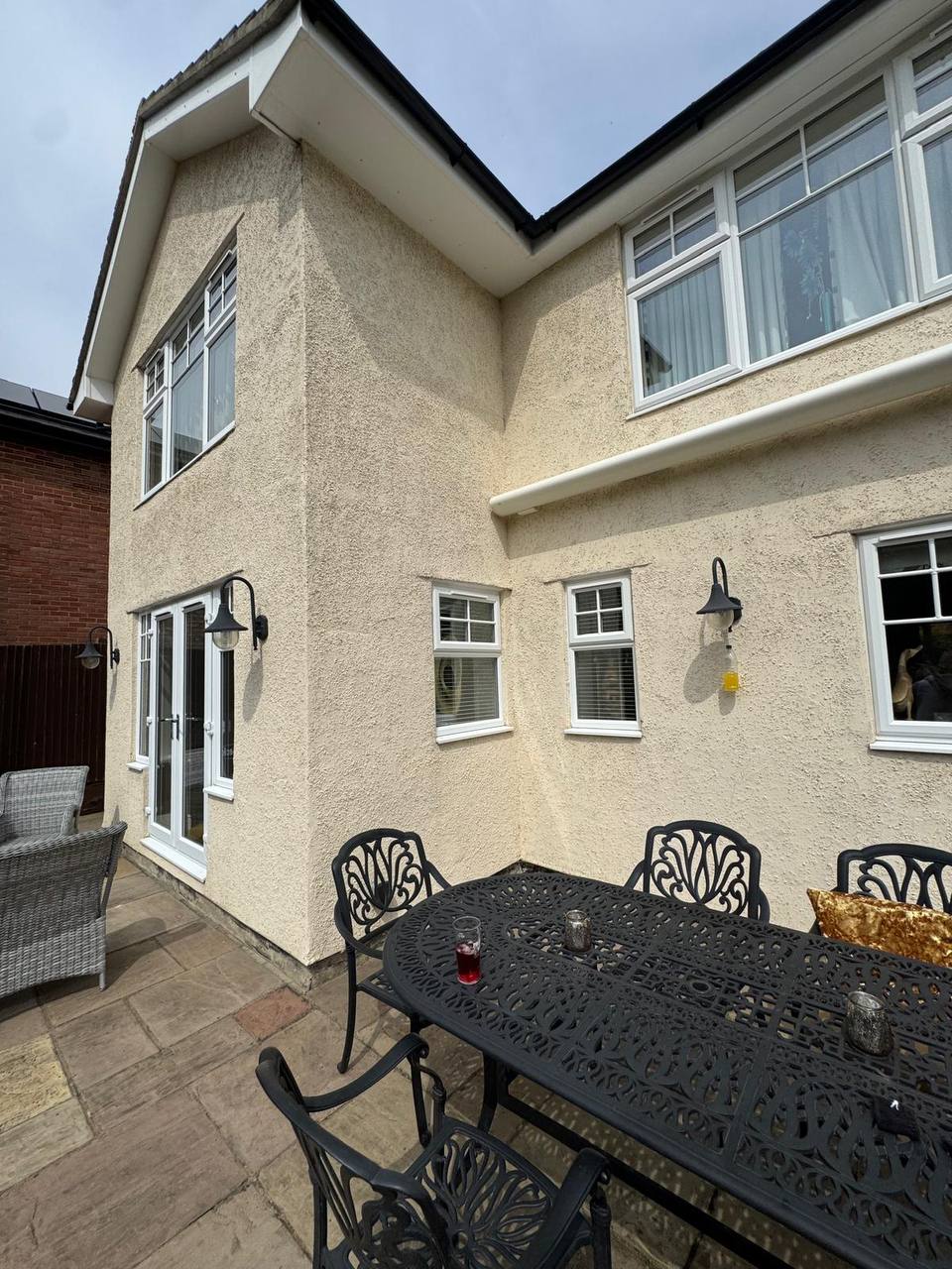 Before: the back of a house in old textured render, stained and patchy